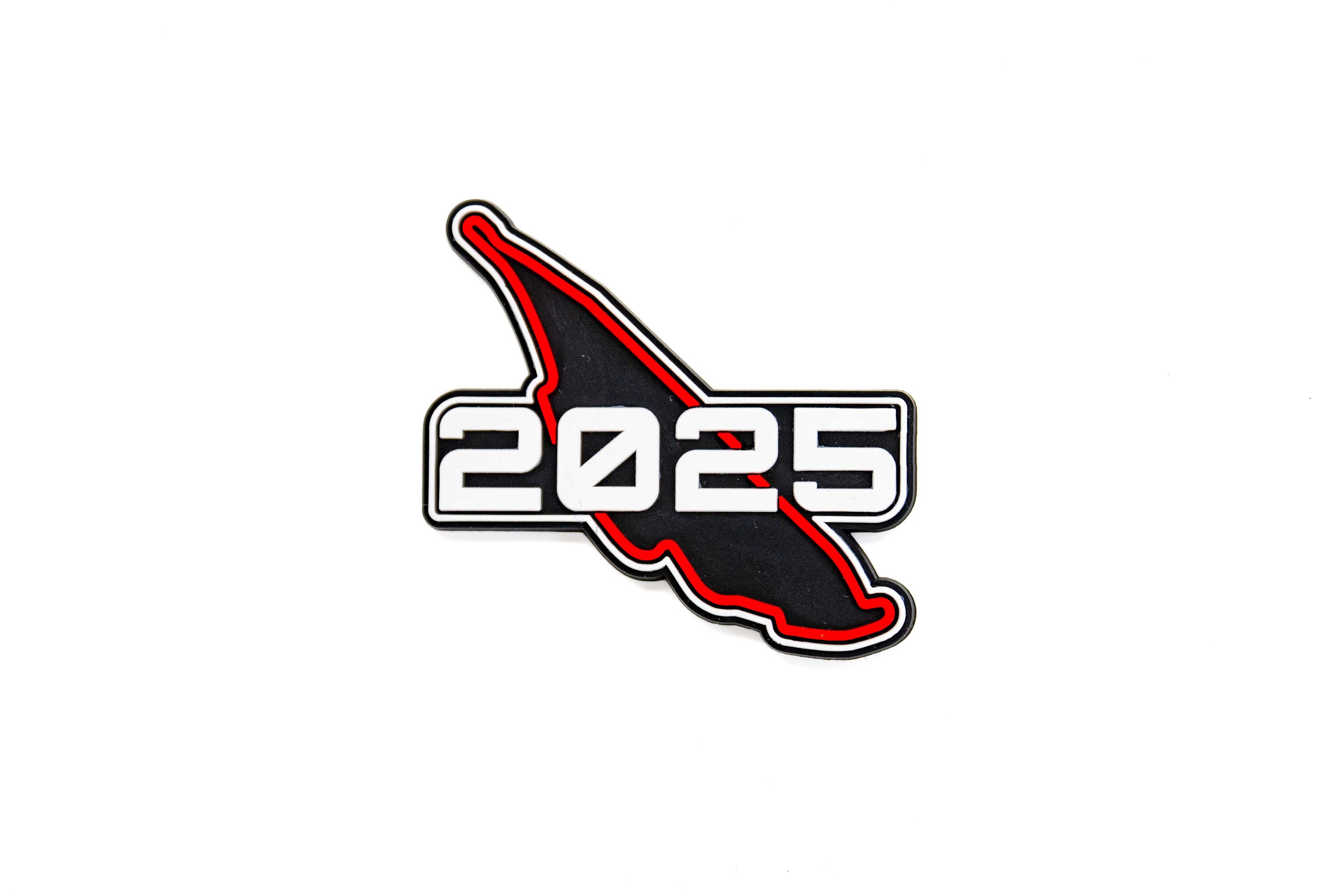 Aimant CGV en forme du circuit noir et rouge, avec inscription ‘2025’ en blanc.