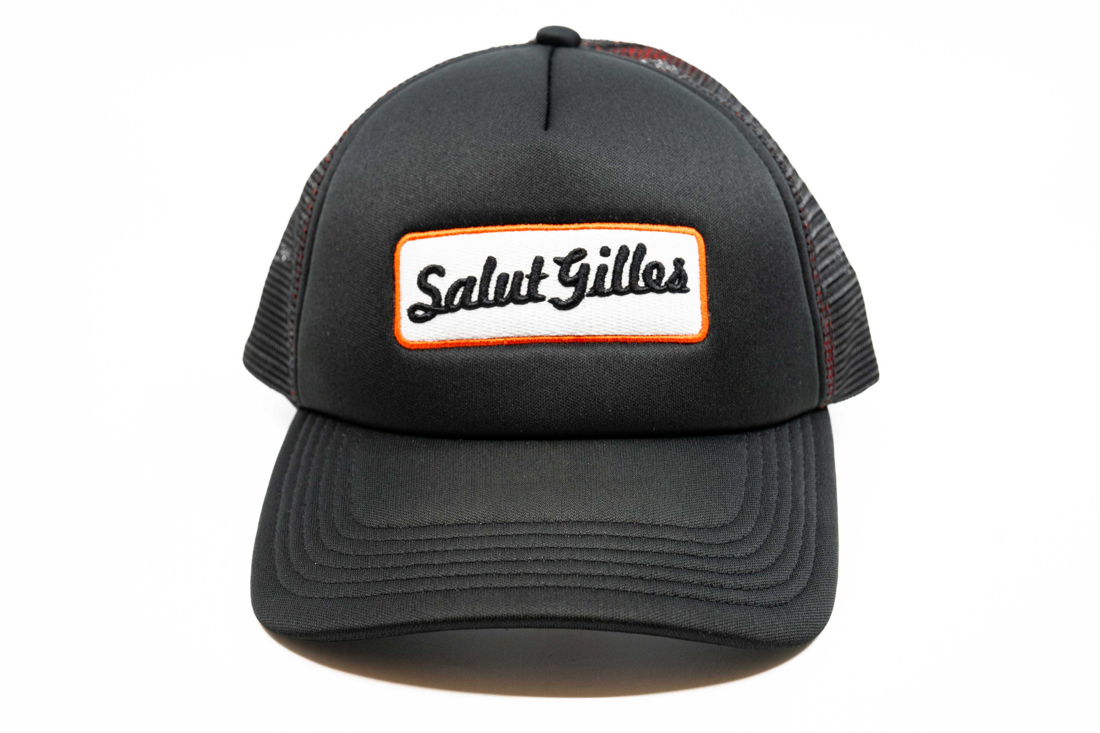 Casquette trucker noire à plat, vue avant, avec patch ‘Salut Gilles’ centré.