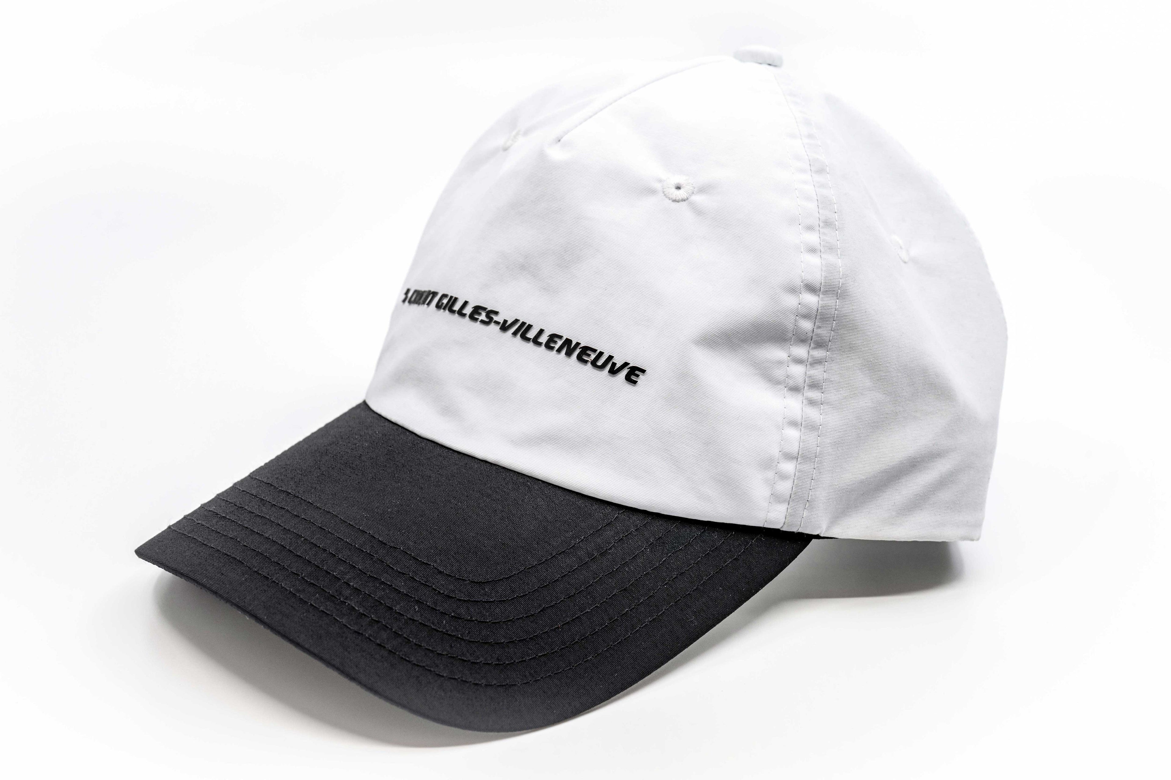 Casquette blanche à visière noire posée sur le côté, montrant la courbure et le style épuré.