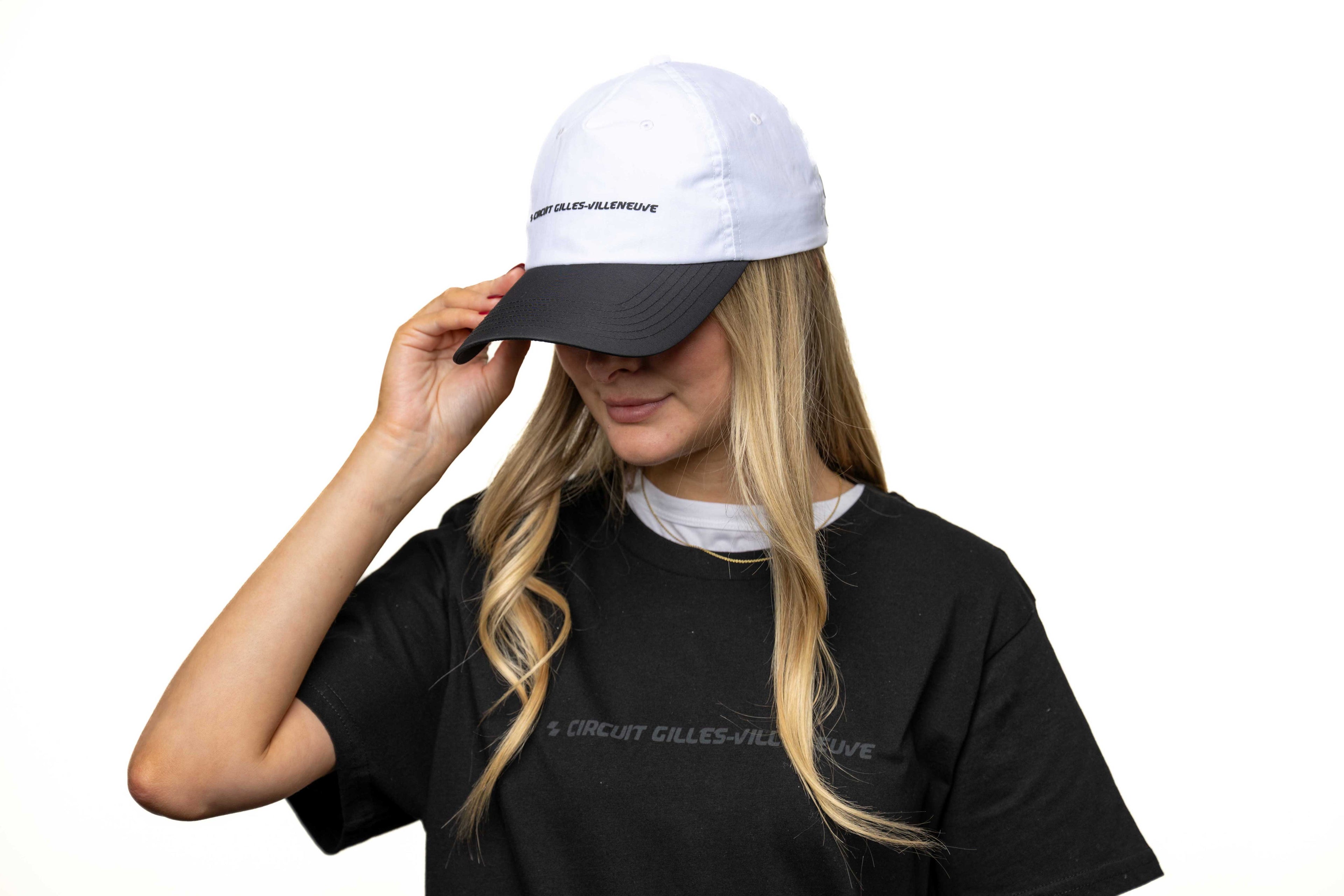 Modèle femme ajustant sa casquette blanche à visière noire, avec logo brodé à l’avant.