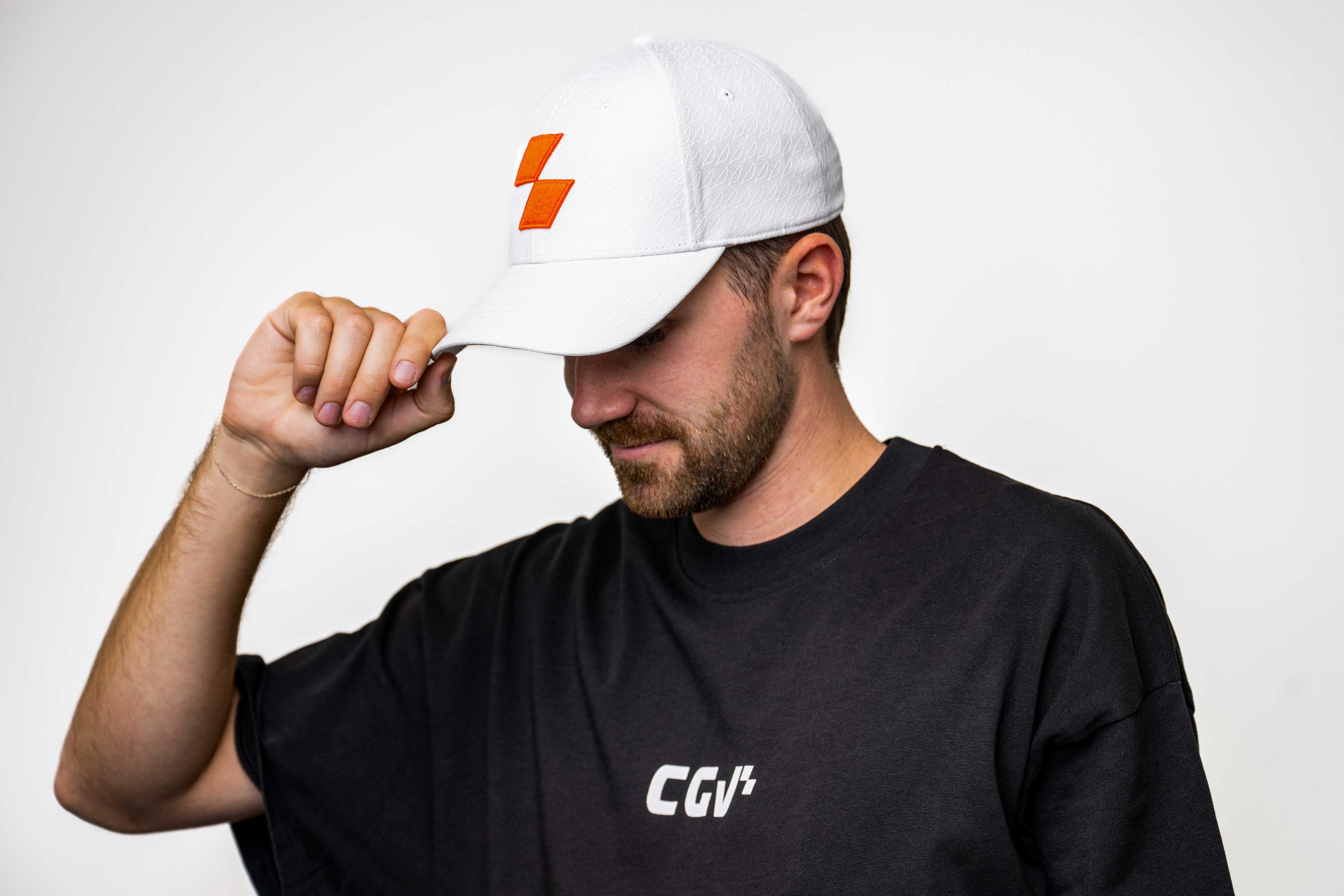 Modèle homme en t-shirt noir portant une casquette blanche avec logo rouge.