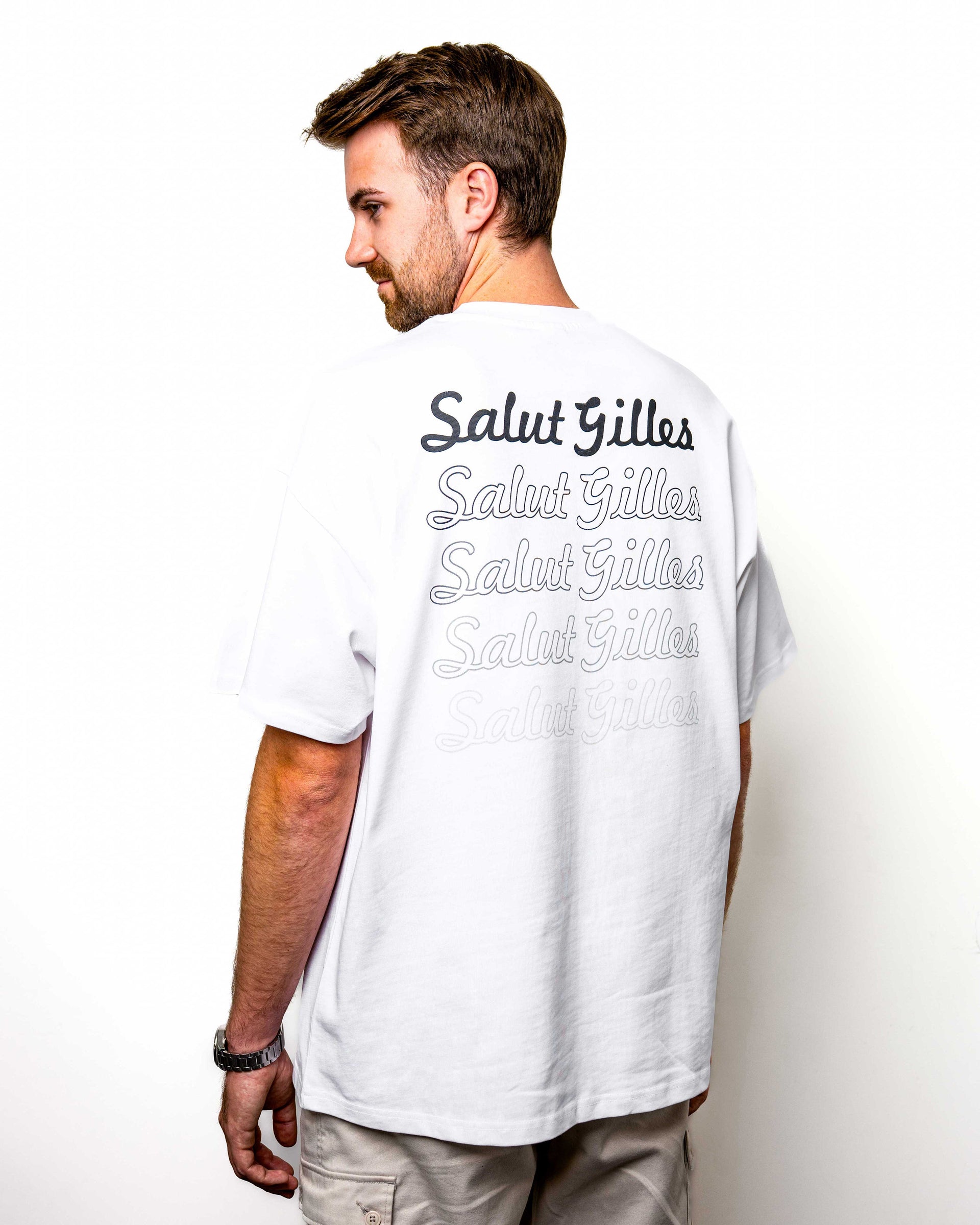 Modèle homme de dos portant un t-shirt blanc ‘Salut Gilles’, avec inscription hommage en noir.