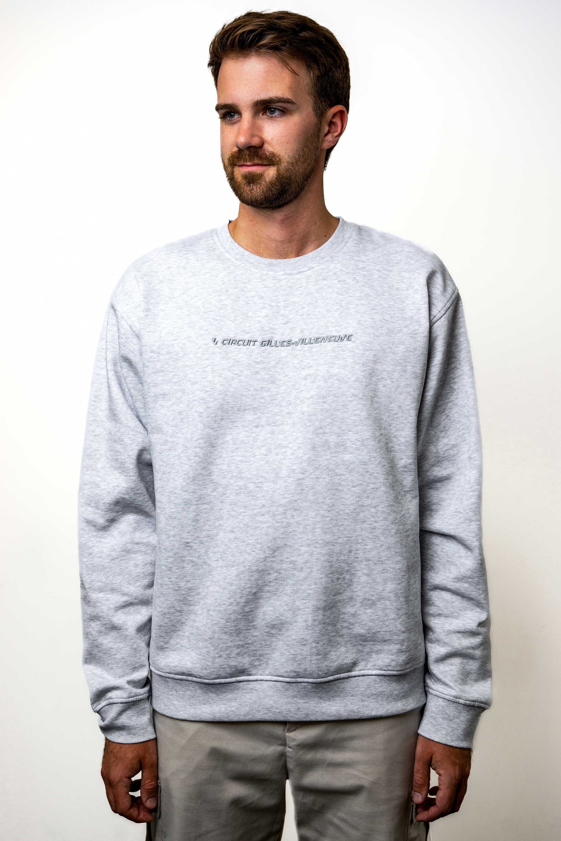 Modèle homme portant un crewneck gris clair avec broderie ton sur ton, vue de face.