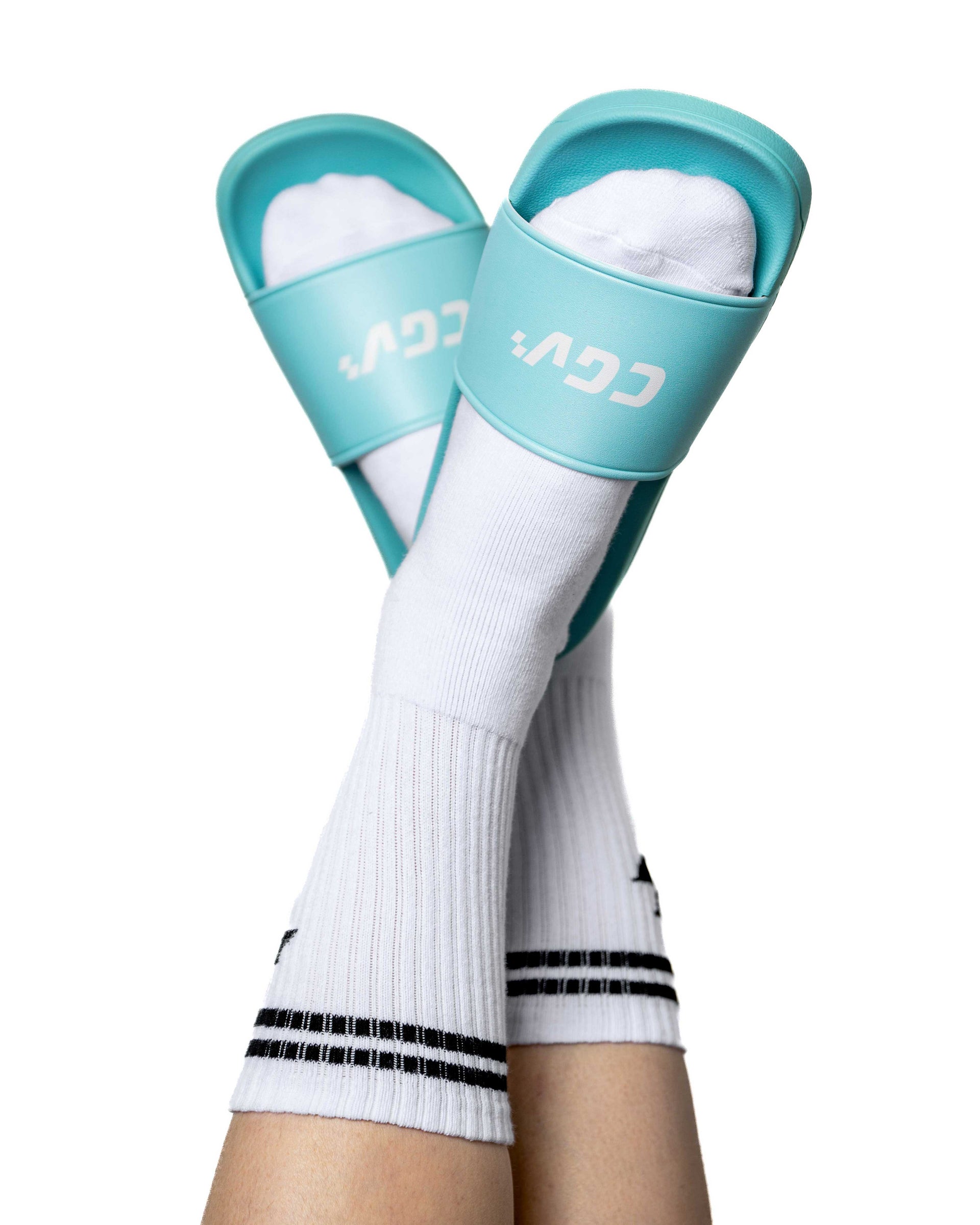 Jambes levées portant des sandales CGV turquoise avec chaussettes blanches rayées.