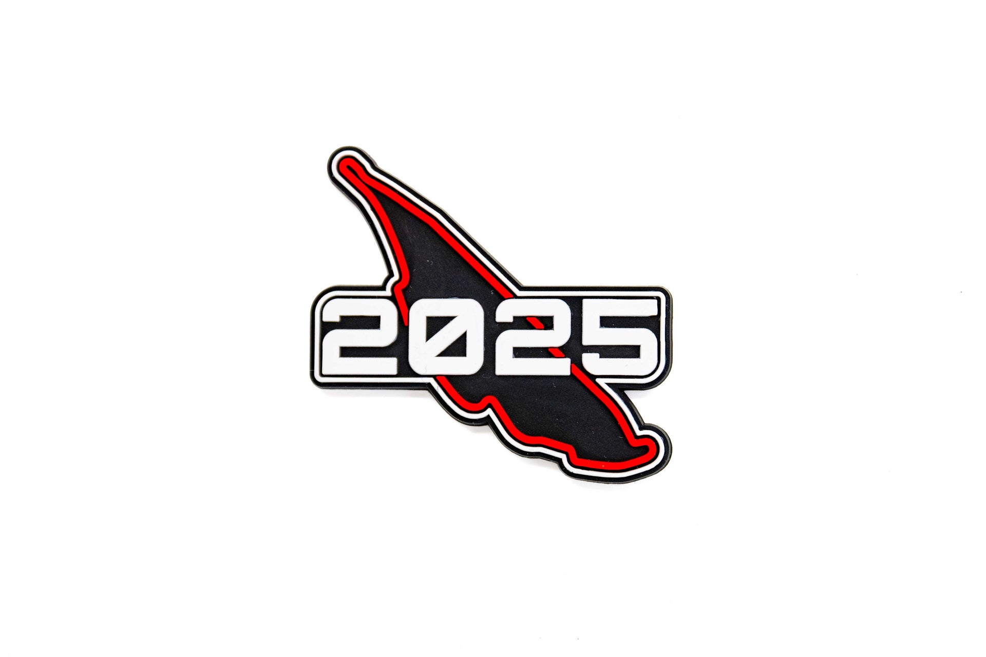 Aimant CGV en forme du circuit noir et rouge, avec inscription ‘2025’ en blanc. 