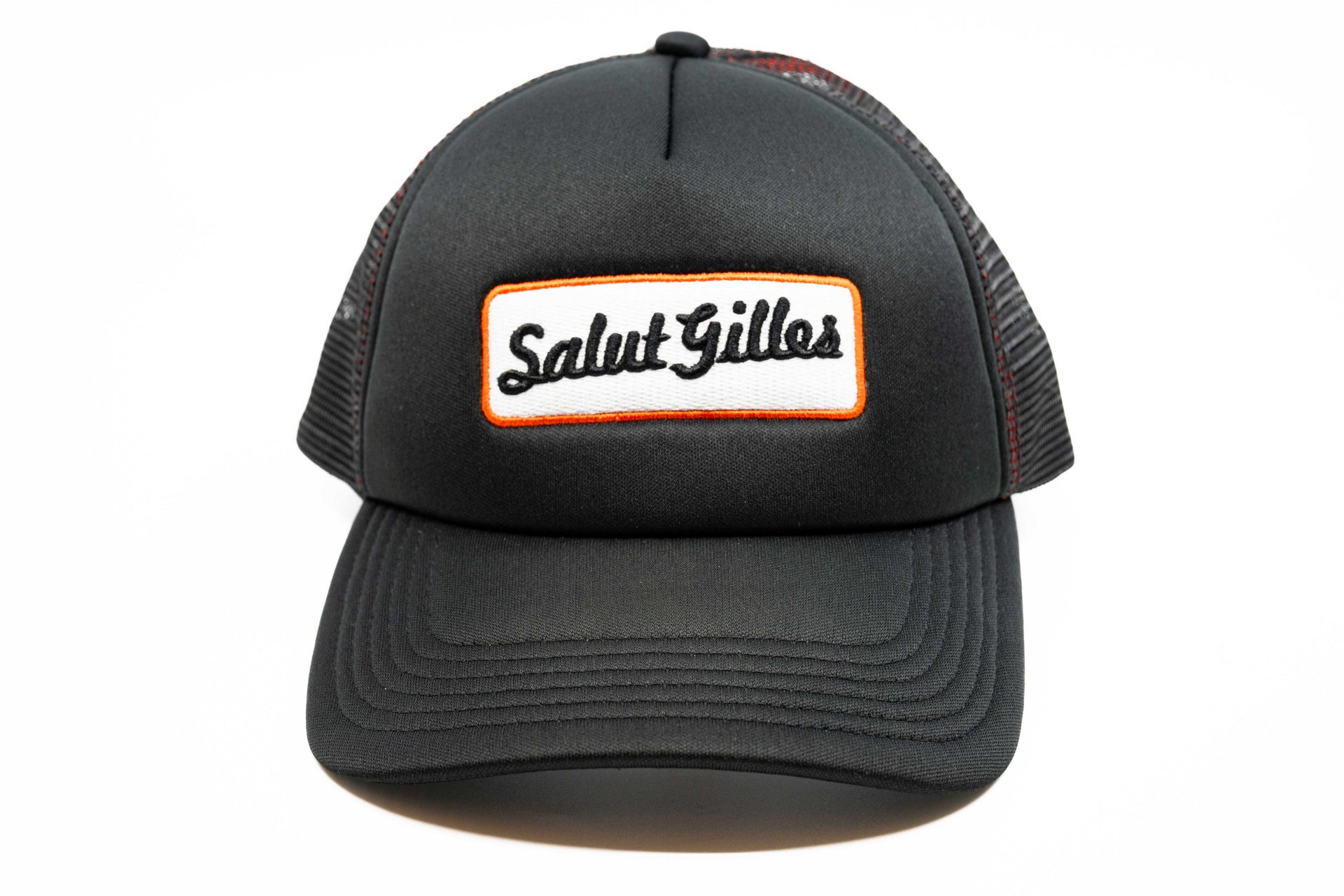 Casquette trucker noire à plat, vue avant, avec patch ‘Salut Gilles’ centré.