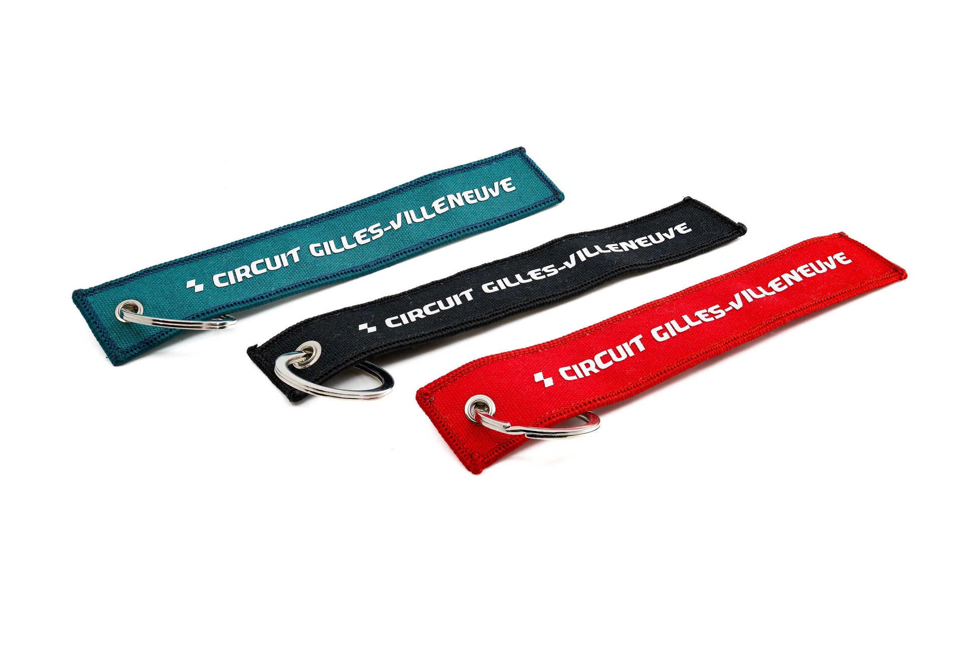 Porte-clés CGV turquoise, noir et rouge posés côte à côte, vue de dessus. 