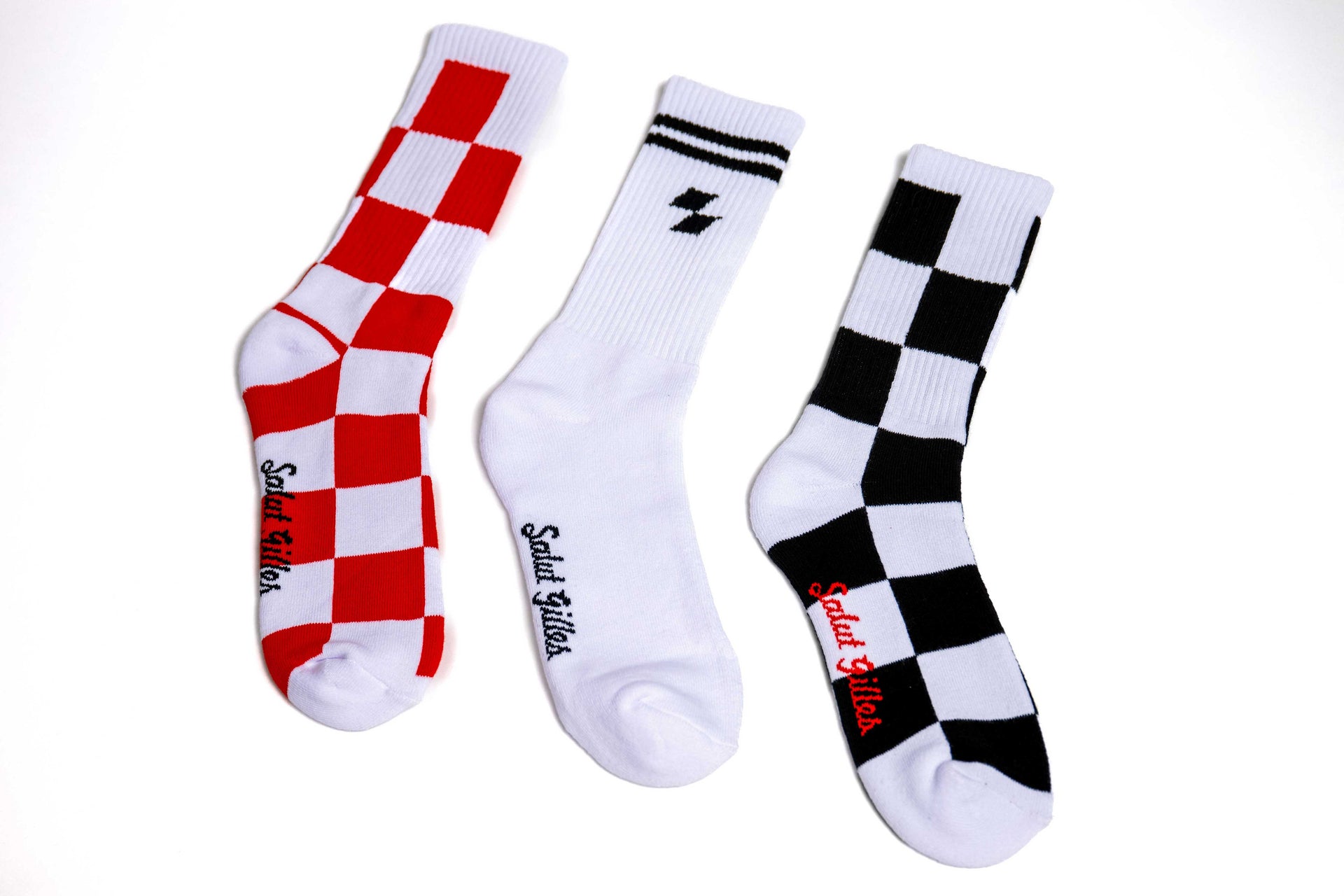 Trio de paires de bas CGV à plat : un blanc avec motif rouge, un noir à damier, un blanc avec logo noir.