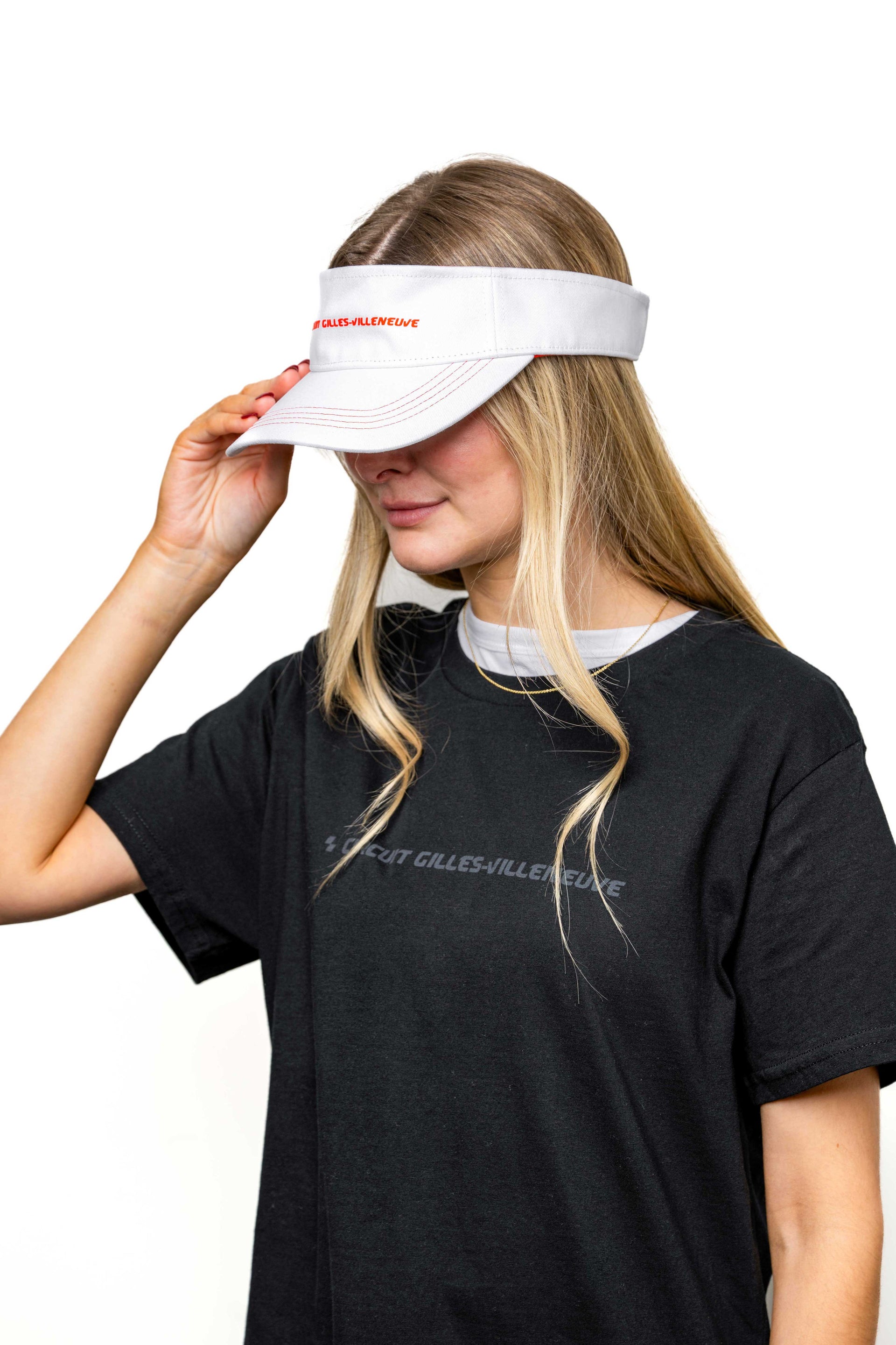 Modèle femme portant une visière blanche à liseré rouge avec logo brodé, vue de profil.